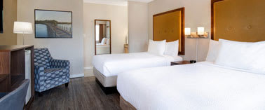 A hotel room with two beds and a chair.