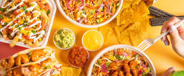 A table full of Mexican food including tacos, nachos and guacamole.