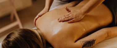 A person is receiving a back massage from a masseur.