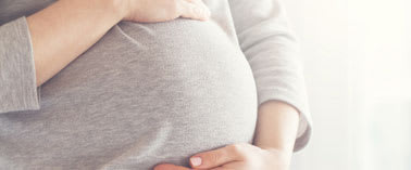 A pregnant woman is holding her belly.