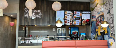 A restaurant with a red booth and a menu board on the wall.