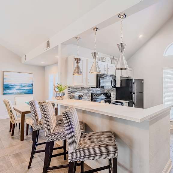A kitchen with a bar area and chairs.