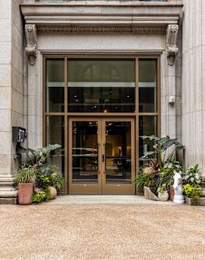 A building with a large glass door flanked by two potted plants.  at The Commonwealth Building, Pittsburgh, 15222