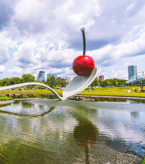 A large red apple sculpture is in the middle of a body of water.