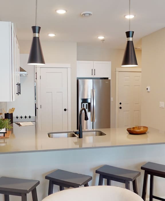 A kitchen with a white counter top and a stainless steel refrigerator.