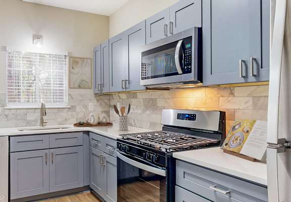 a kitchen with blue cabinets and a stove and a microwave