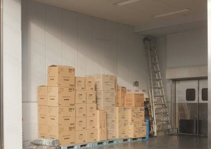 A large room with a ladder and stacks of boxes.