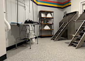 Thumbnail 2 of 10 - A room with a metal staircase and a table with a white container on it.