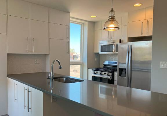 Apartment kitchen at Highpoint Lakeview on Sheffield in Chicago with white cabinetry and stainless steel appliances