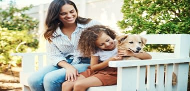 A woman and a child are sitting on a white bench with a dog at Monaco at McCormick Ranch, Arizona 85258