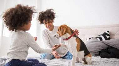 two women sitting on a bed with a dog