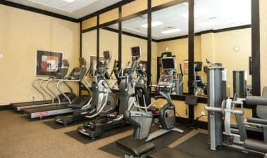 a gym with cardio machines and a tv