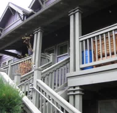 A porch with a white railing and a blue planter.