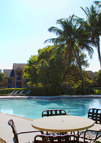 a swimming pool with a table and chairs next to it at Indian Trace, West Palm Beach, FL 33407