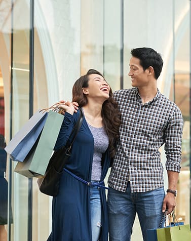 a man and woman holding shopping bags and looking at each other
