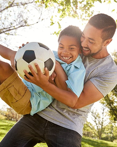 Lifestyle photo of a father and son playing soccer