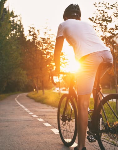 a man riding a bike down a road at sunset