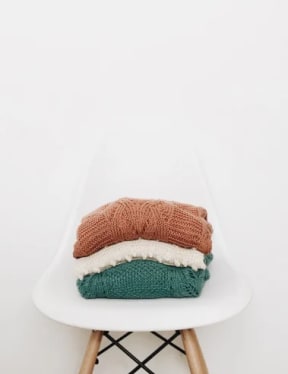 a pile of sweaters sitting on top of a chair