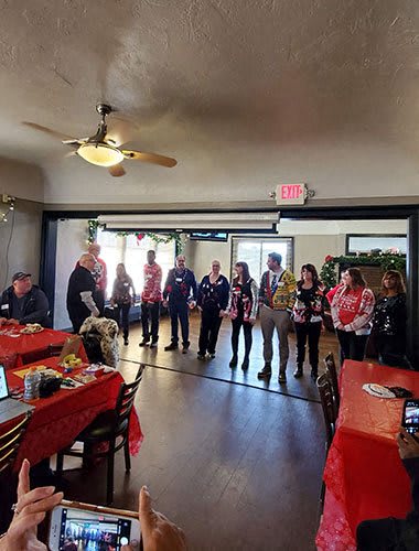 a group of people standing in a room with a christmas party
