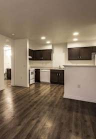 A kitchen with dark wood floors and white walls.