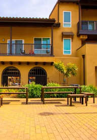 A yellow building with a balcony and a bench in front.