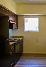 A kitchen with a black refrigerator and stove top oven.