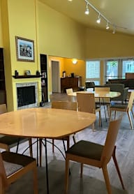A room with a fireplace and chairs around a table.