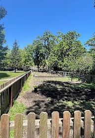A wooden fence in front of a grassy area with trees.