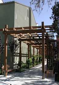 A wooden pergola is in front of a building.