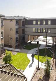 A person is walking in a courtyard surrounded by buildings.