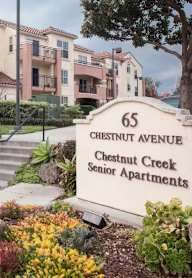 A sign for Chestnut Creek Senior Apartments is in front of a building.