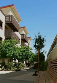 A row of apartment buildings with trees in front.