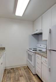 A kitchen with a white refrigerator and a stainless steel sink.