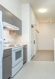 A kitchen with white appliances and grey cabinets.