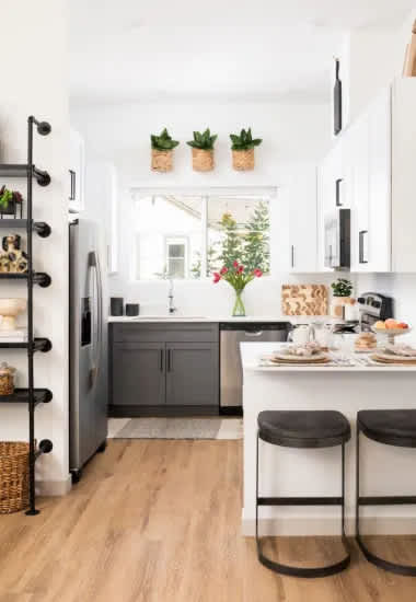 A kitchen with a white refrigerator and a dining table with two chairs.