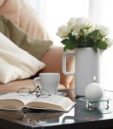 a wicker chair with a white pillow next to a green plant