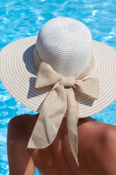 a person holding a hat up to a swimming pool