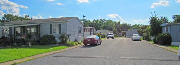 A street with cars and houses on both sides.