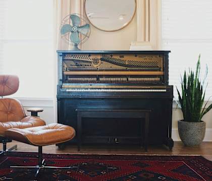 A brown leather chair sits in front of a black piano.