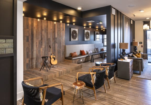 a living room with chairs and a guitar on the wall