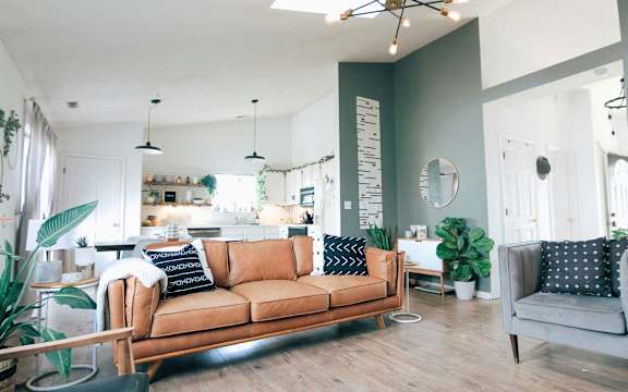 A living room with a brown sofa and a grey armchair.