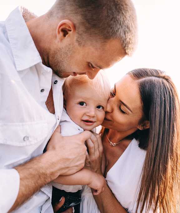 A man and woman holding a baby outdoors.