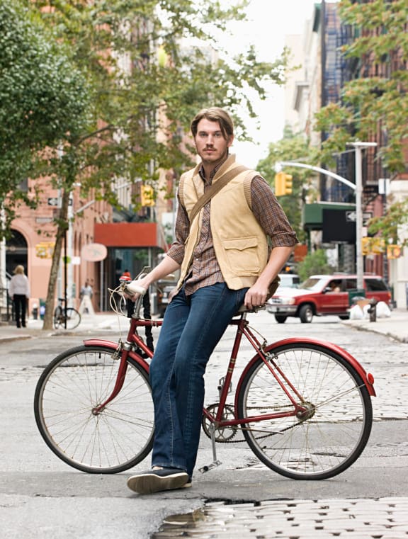 a man sitting on a red bike on a city street