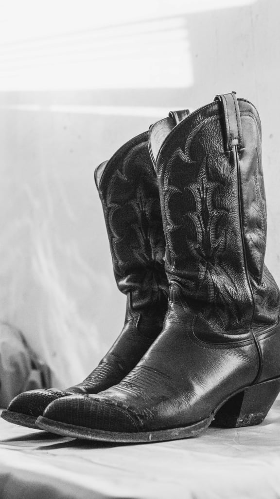 a black and white photo of a pair of black cowboy boots