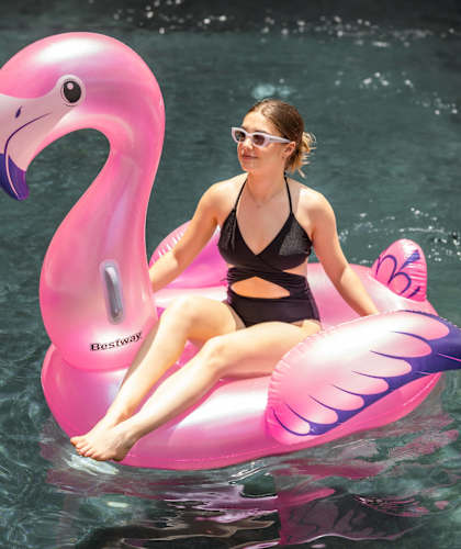 a woman sitting on a pink flamingo float in the water
