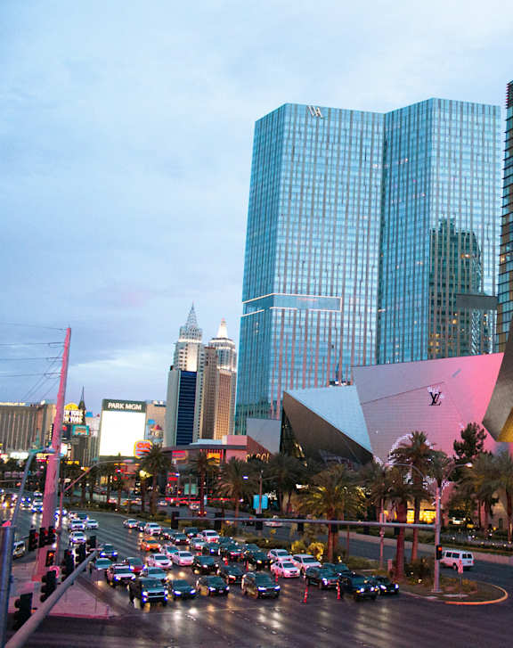 A busy street in a city with tall buildings and cars driving.