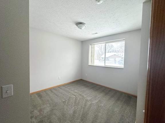 A room with a window and carpeted floor.