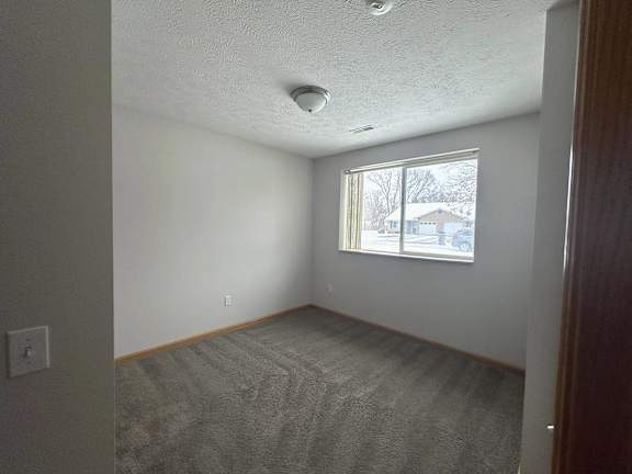 A room with a window and a carpeted floor.