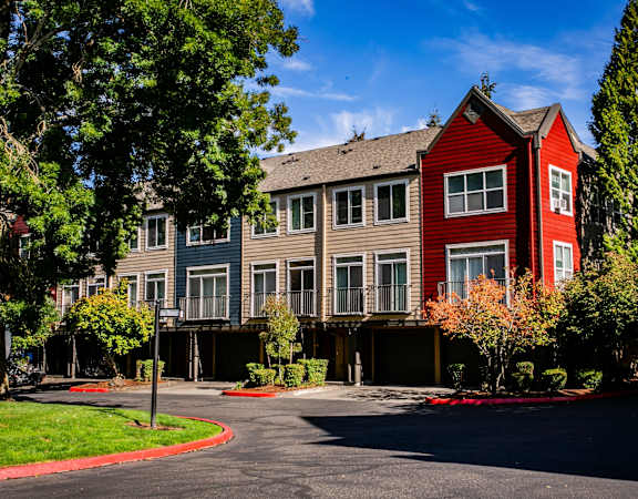 an apartment building with a red exterior and a parking lot