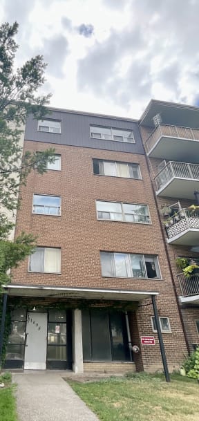 a brick apartment building with balconies and a walkway in front of it
